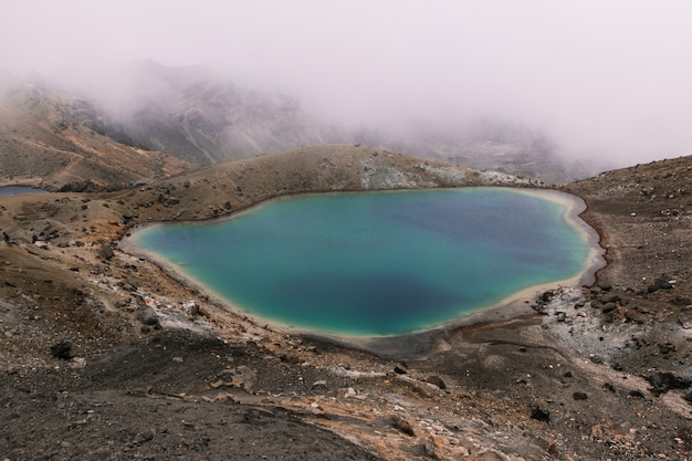 Piccolo lago nel mezzo del deserto vicino a una montagna in una giornata nebbiosa