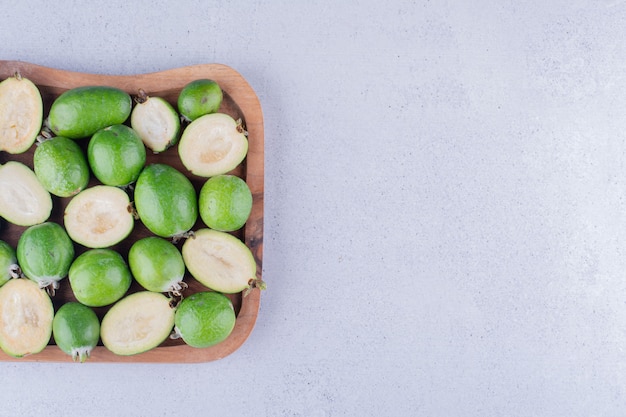 Piccolo mucchio di feijoas infagottato in un vassoio di legno su sfondo marmo. Foto di alta qualità