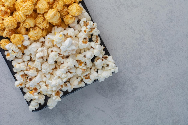 Piccolo piatto di caramelle popcorn e popcorn salato sulla superficie in marmo
