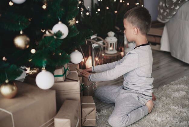 Piccolo ragazzo che organizza i regali di Natale