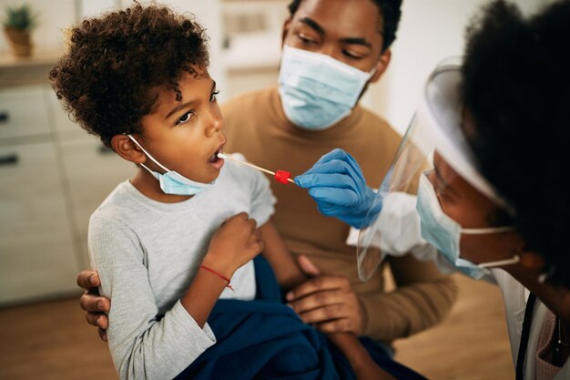 Piccolo ragazzo nero che ha un test PCR a casa durante la pandemia di coronavirus