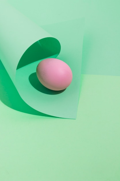 Piccolo uovo di Pasqua rosa con carta arrotolata sul tavolo