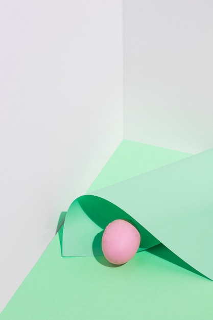 Piccolo uovo di Pasqua rosa con foglio di carta sul tavolo