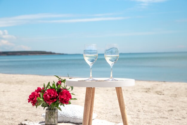 Picnic in riva al mare con fiori e un bicchiere di champagne. Il concetto di vacanza.