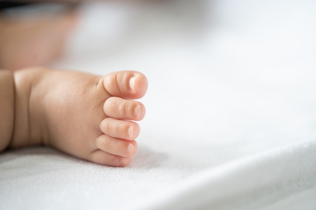 Piedi del bambino nel letto bianco.