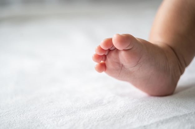 Piedi del bambino nel letto bianco.