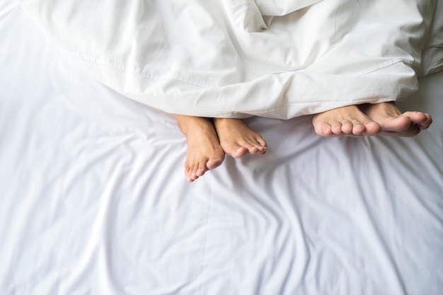 Piedi di coppia in letto comodo.