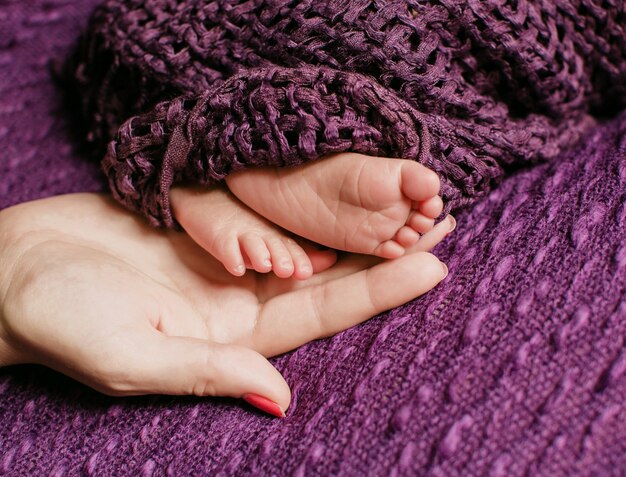 Piedi di piccolo bambino si trovano sul braccio della madre