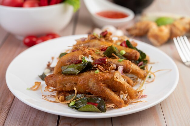 Piedi di pollo fritto con erbe su un piatto bianco e salsa di immersione.