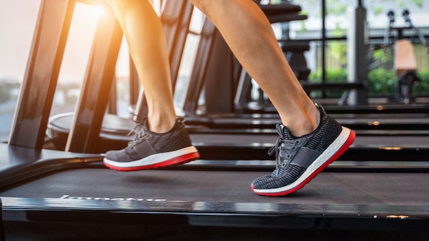 Piedi maschili in scarpe da ginnastica in esecuzione sul tapis roulant in palestra. Concetto di esercizio.