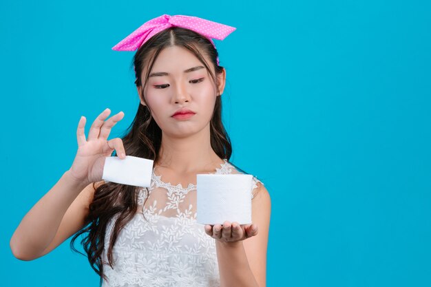 Pigiama bianco da portare della ragazza che tiene una carta del rotolo nella mano sull'azzurro.