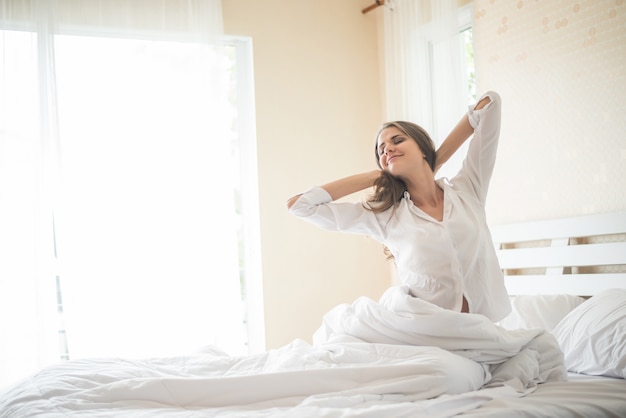 Pigro giovane donna seduta in camera da letto