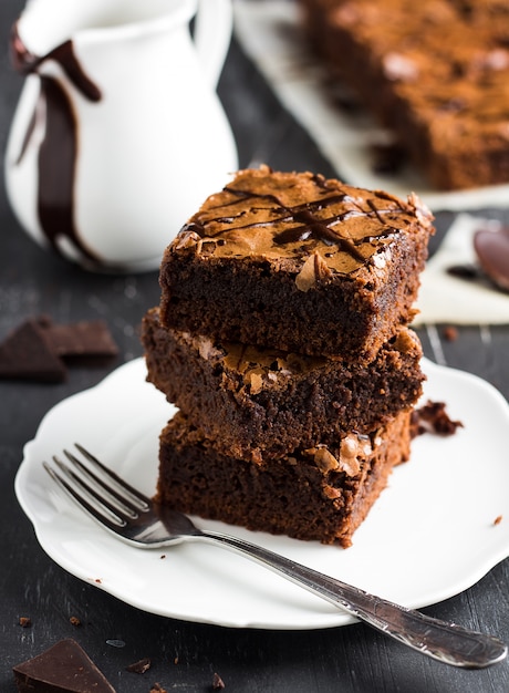 Pila del pezzo del dolce del brownie del cioccolato sulle pasticcerie casalinghe del piatto