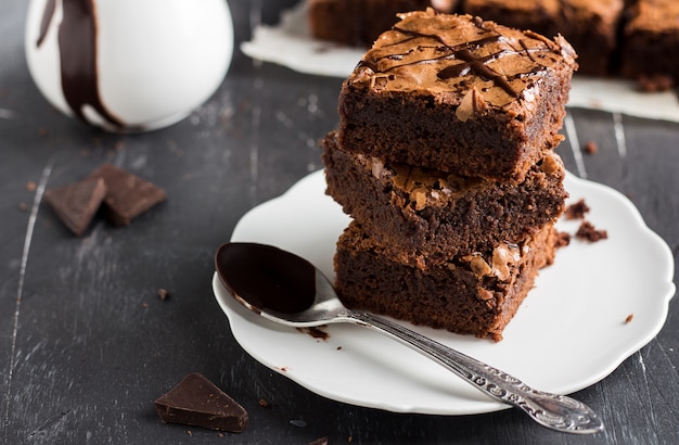 Pila del pezzo del dolce del brownie del cioccolato sulle pasticcerie casalinghe del piatto