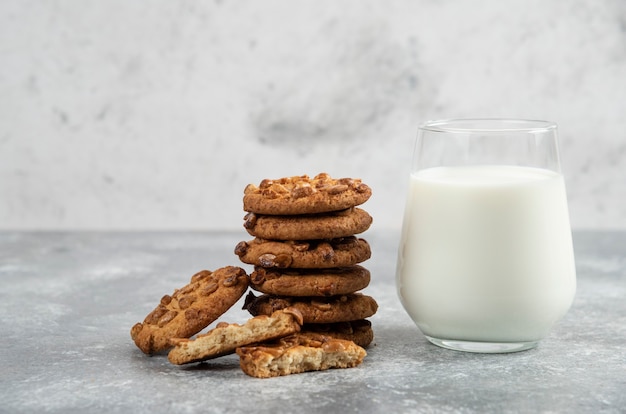 Pila di biscotti con arachidi e miele con un bicchiere di latte sul tavolo di marmo.