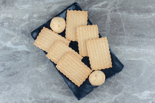 Pila di biscotti fatti in casa sul piatto di ceramica nero.