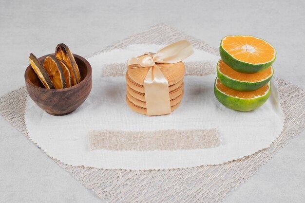 Pila di biscotti legati con fiocco e fette di mandarino su sfondo marmo. Foto di alta qualità