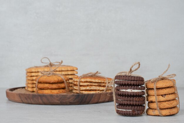 Pila di biscotti legati con una corda sul piatto di legno.