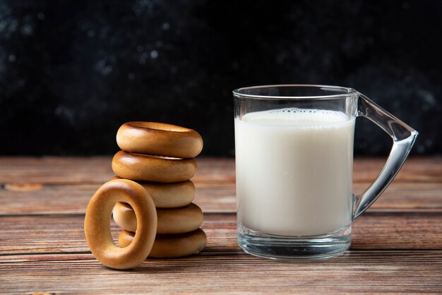 Pila di biscotti rotondi e bicchiere di latte sulla tavola di legno.