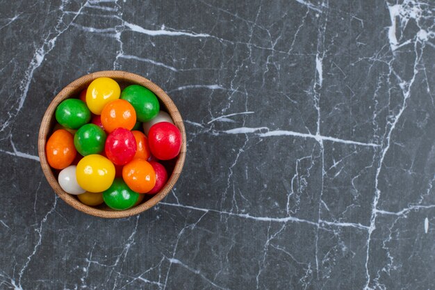 Pila di caramelle colorate nella ciotola di legno