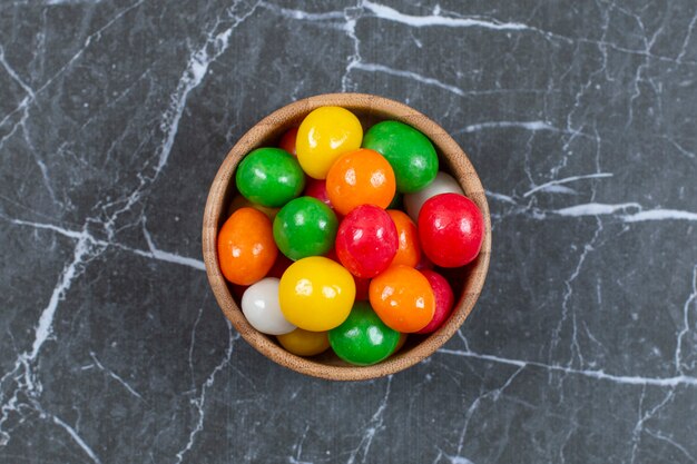 Pila di caramelle colorate nella ciotola di legno.