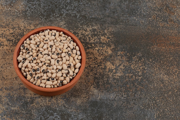 Pila di fagioli bianchi crudi in una ciotola di ceramica.