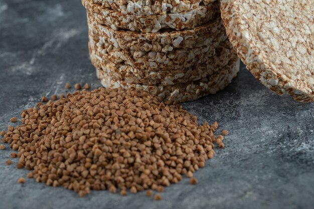 Pila di fette biscottate e mucchio di grano saraceno sulla superficie di marmo