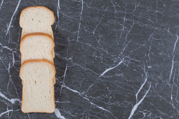 Pila di fette di pane fresco su grigio.