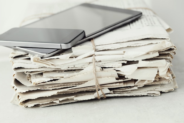 Pila di giornali con tavoletta digitale e smartphone