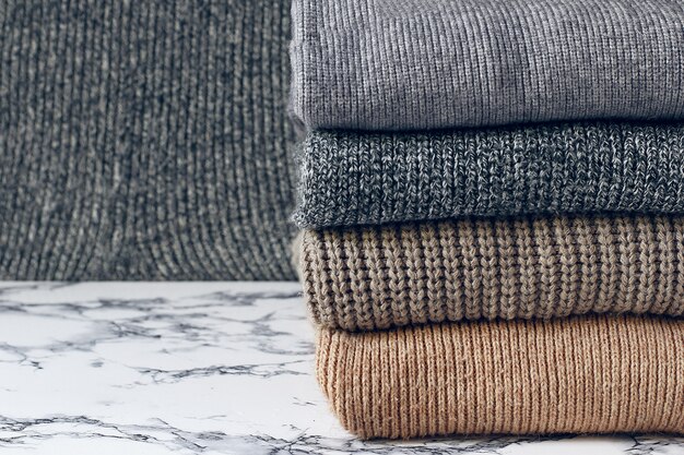 Pila di maglioni a maglia accoglienti. Concetto autunno-inverno, maglioni di lana lavorati a maglia. Mucchio di abiti invernali a maglia, maglioni, maglieria