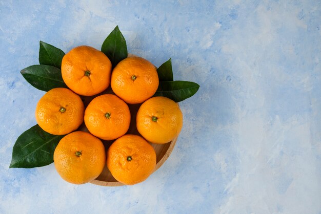 Pila di mandarini clementine e foglie sul piatto di legno