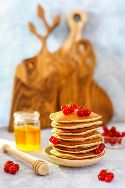 Pila di pancake fatti in casa con sciroppo di miele e frutti di bosco.