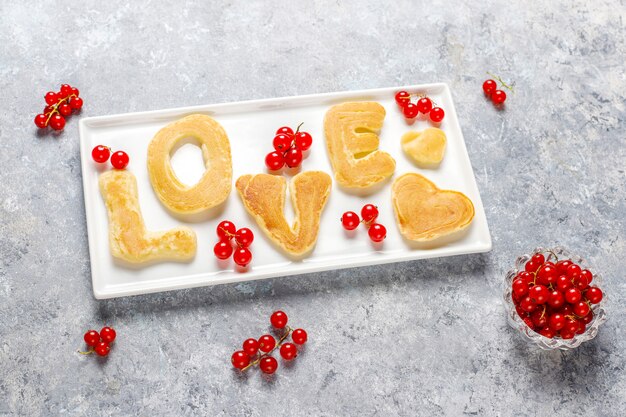 Pila di pancake fatti in casa con sciroppo di miele e frutti di bosco.