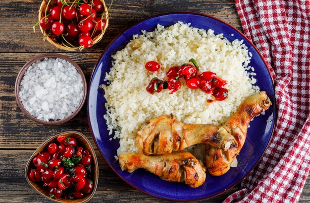 Pilaf con carne di pollo, ciliegia, sale in un piatto su un asciugamano di legno e cucina.