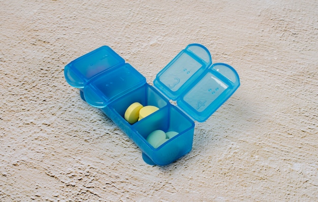 Pillole colorate nella disposizione della scatola ad alto angolo