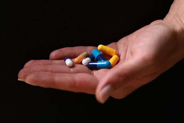 Pillole mediche colorate nella mano.