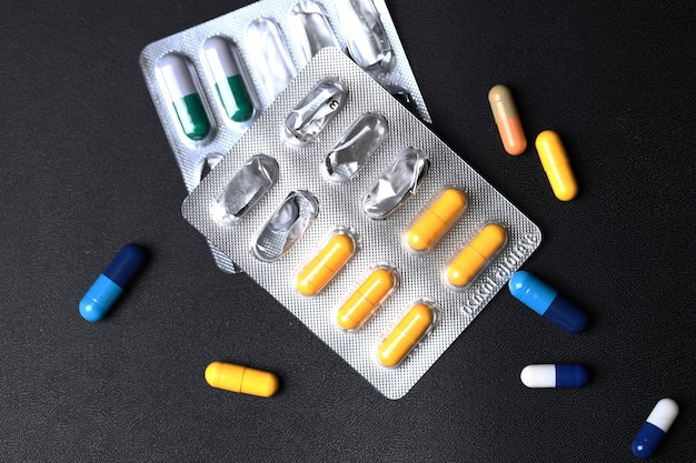 Pillole mediche colorate su sfondo nero. Vista dall'alto.