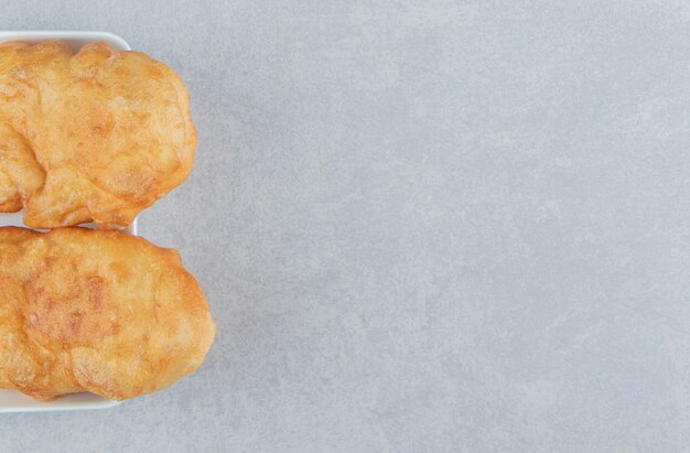 Piroshki al forno con patate in una ciotola bianca.