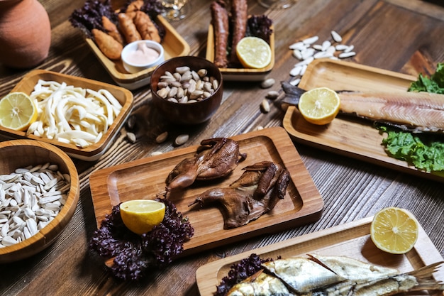 Pistacchi affumicati dei semi del formaggio della quaglia del pesce affumicato degli spuntini della birra di vista laterale con il limone sulla tavola