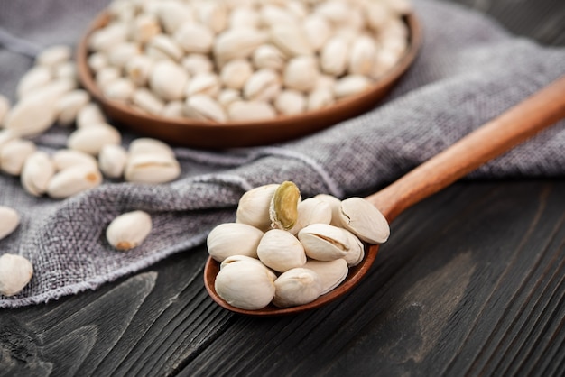 Pistacchi in un cucchiaio di legno. Ciotola di legno con pistacchi di noci. su uno sfondo di legno. Cibo sano e spuntino, cibo vegetariano biologico.