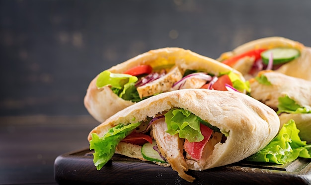 Pita ripiena di pollo, pomodoro e lattuga sul tavolo di legno. Cucina mediorientale.