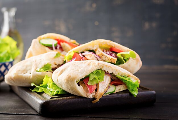 Pita ripiena di pollo, pomodoro e lattuga sul tavolo di legno. Cucina mediorientale.