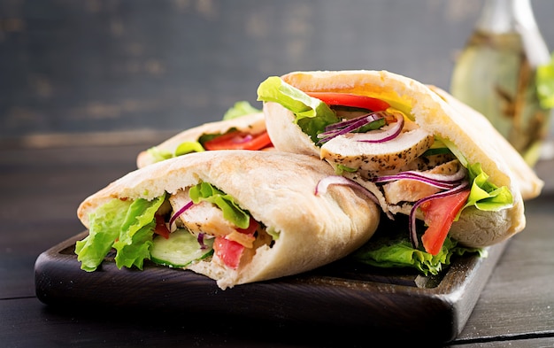 Pita ripiena di pollo, pomodoro e lattuga sul tavolo di legno. Cucina mediorientale.