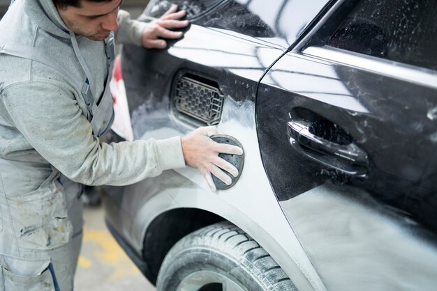 Pittore di auto che prepara auto per la pittura in officina