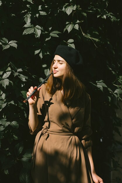 Pittore femminile che dipinge in città. Una donna che indossa un abito color cachi e un cappello nero