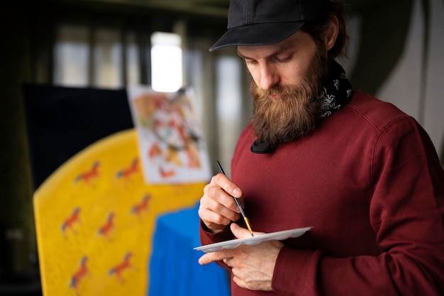 Pittore maschio in studio usando l'acquerello sulla sua arte