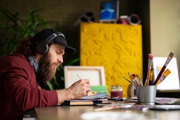 Pittore maschio in studio usando l'acquerello sulla sua arte