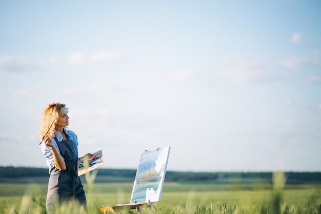 Pittura dell&#39;artista della donna con le pitture ad olio in un campo