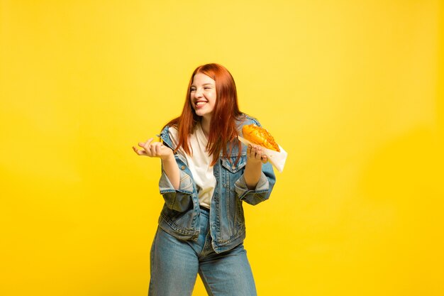 È più facile essere follower. Non è necessario scattare foto con il cibo. La donna caucasica è su sfondo giallo. Bello modello femminile dei capelli rossi. Concetto di emozioni umane, espressione facciale, vendite, annuncio.