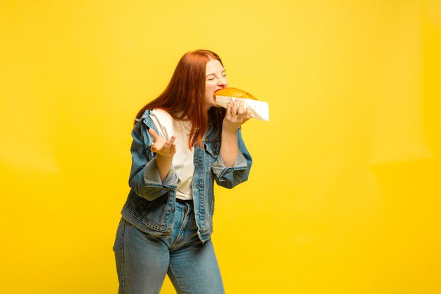 È più facile essere follower. Non è necessario scattare foto con il cibo. La donna caucasica è su sfondo giallo. Bello modello femminile dei capelli rossi. Concetto di emozioni umane, espressione facciale, vendite, annuncio.